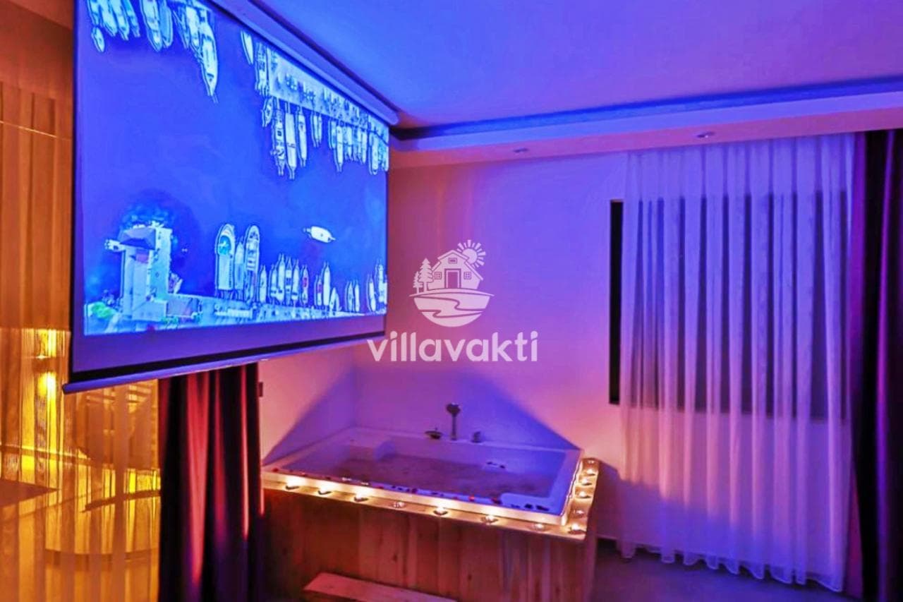 Mor ışıklandırmalı yatak odasında jakuzi ve dev projeksiyon ekranı.