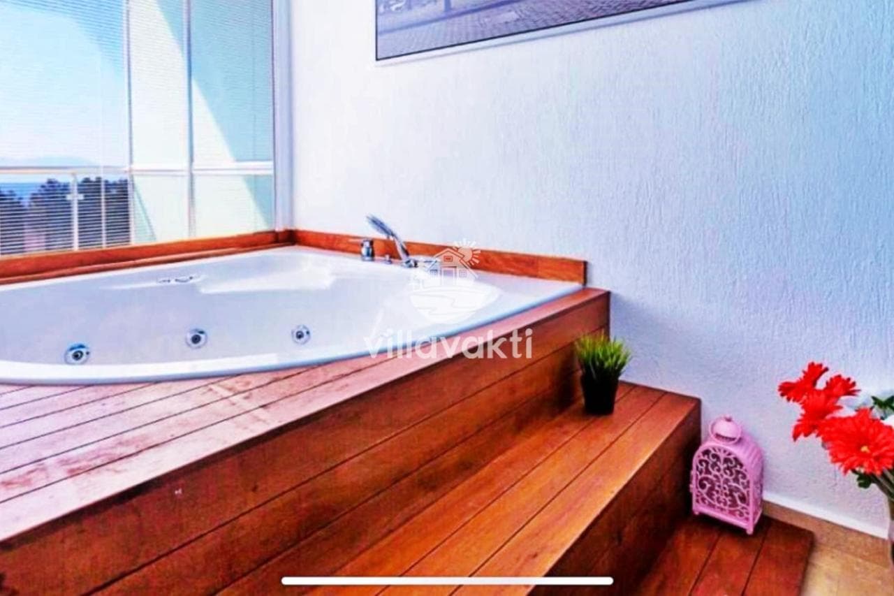 Pencere önünde ahşap platforma yerleştirilmiş büyük jakuzi.
