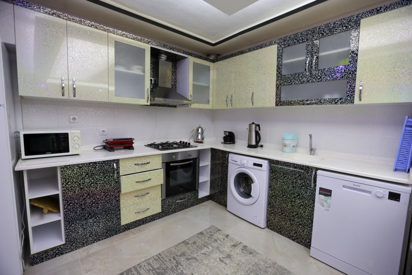 Sarı ve siyah desenli dolaplara sahip modern mutfakta çamaşır ve bulaşık makinesi.