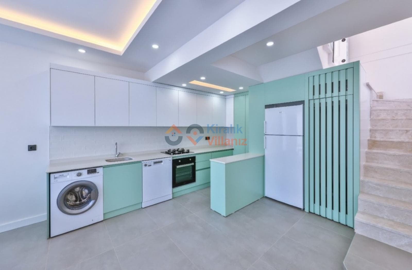 Mint yeşili dolaplı ve beyaz tezgahlı modern mutfak, çamaşır makinesi ve mermer merdivenler.