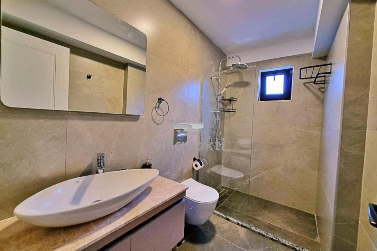 Bej seramik kaplı, duşakabinli ve uzun aynalı modern banyo.
