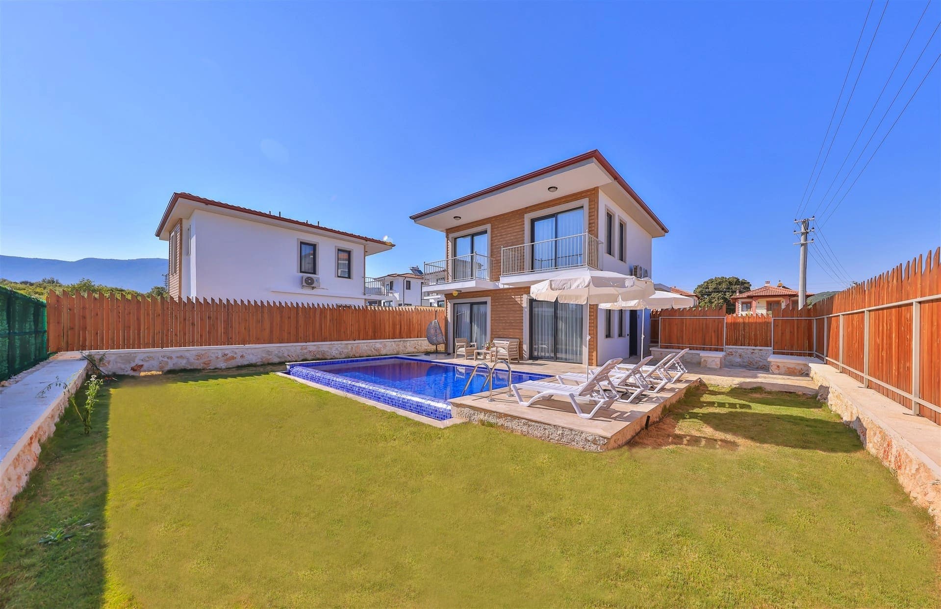 Bahçesinde yüzme havuzu ve şezlonglar bulunan iki katlı villa