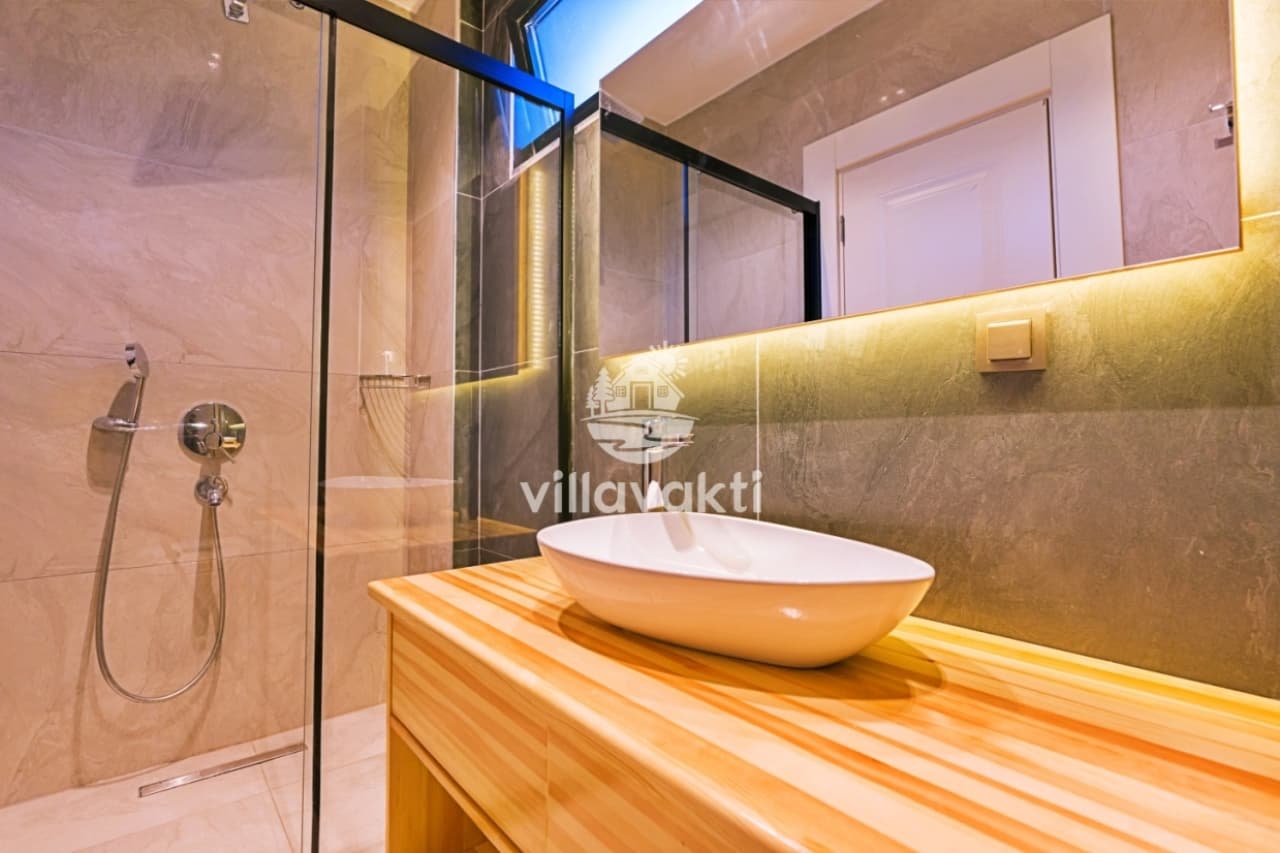 Aynalı lavabo tezgâhı ve duş alanına sahip modern banyo
