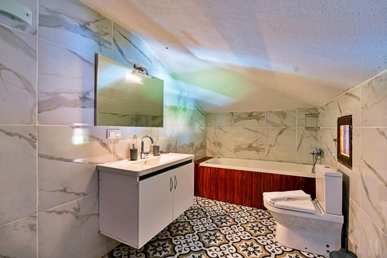 Mermer duvarlı, küvetli ve aynalı banyo iç mekan görünümü.
