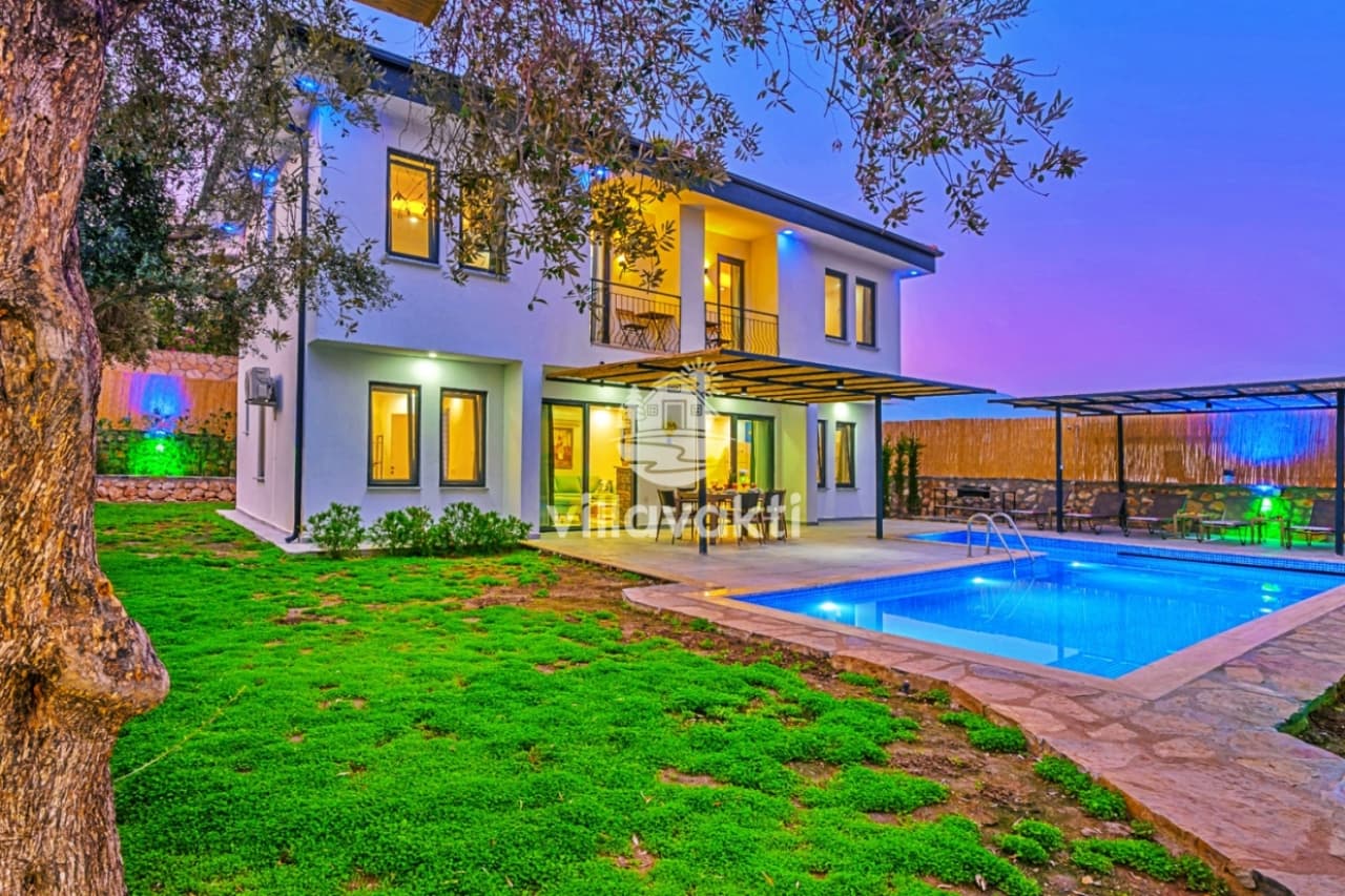 Akşam ışıklandırmalı havuzun bulunduğu iki katlı villa dış cephesi.