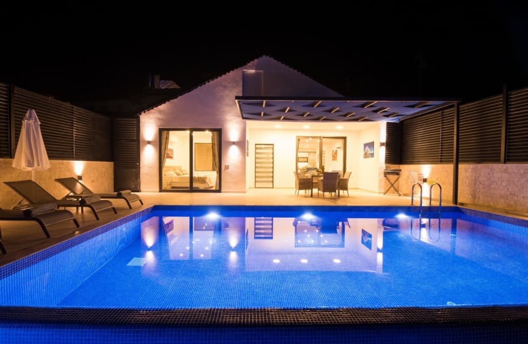 Gece aydınlatmalı özel havuzu, şezlongları ve veranda alanı bulunan müstakil villa.