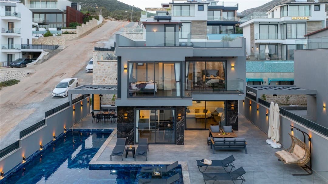 Özel havuzlu, geniş teraslı, modern mimariye sahip iki katlı gri villa ve çevresindeki yerleşim alanı.