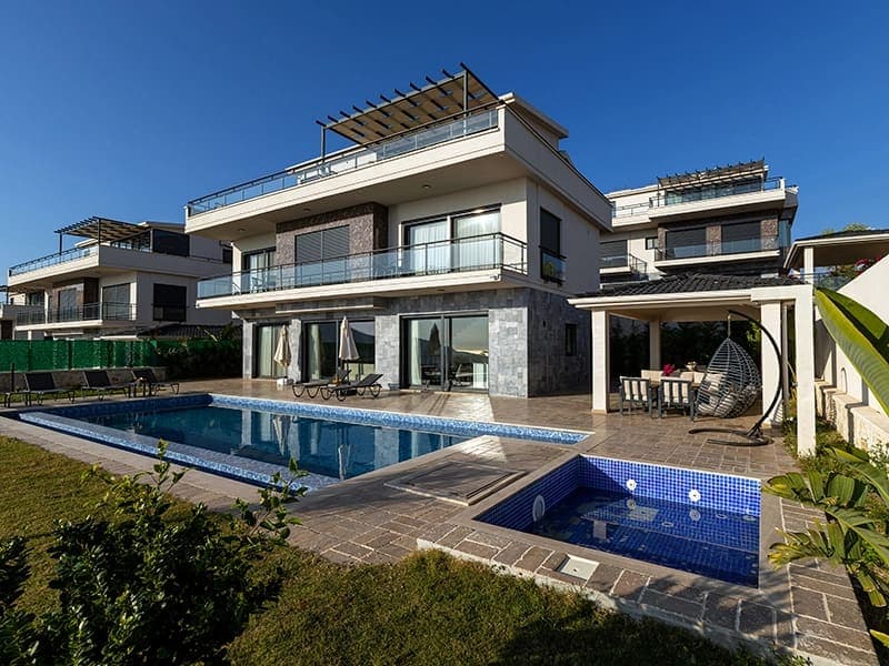Yüzme havuzlu, çim bahçeli ve çardaklı modern villa dış cephesi.