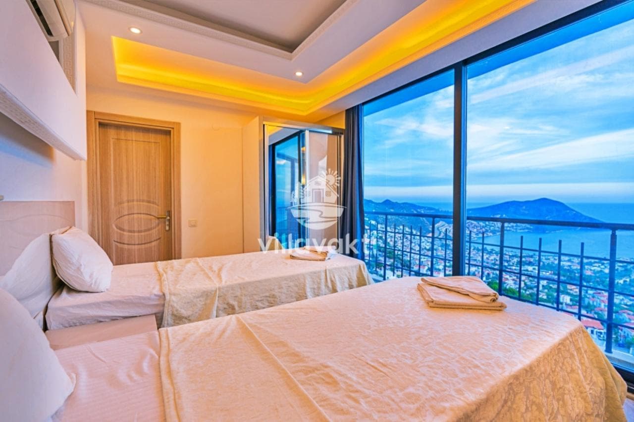İki tek yataklı, balkon kapısından panoramik deniz ve dağ manzarası görünen yatak odası.