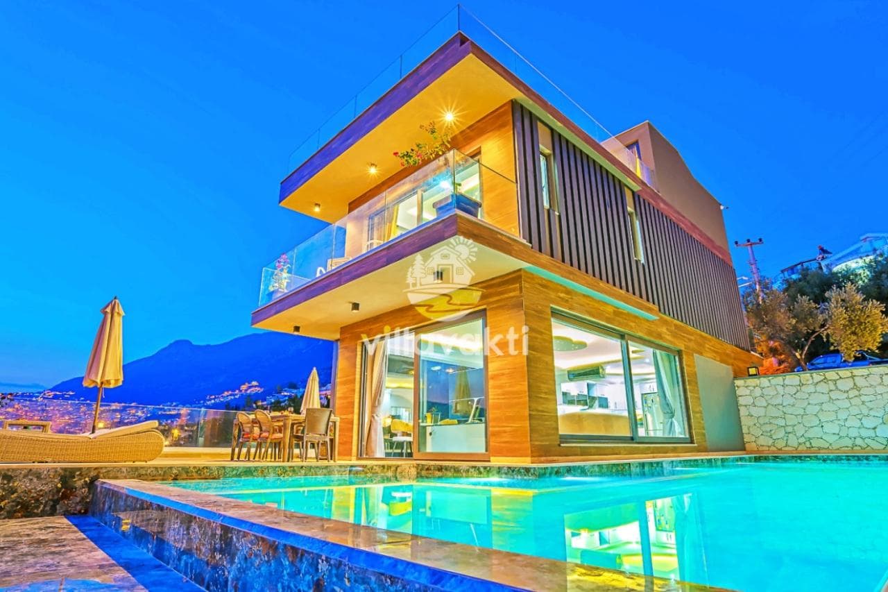 Akşam ışıklandırmalı, modern ahşap kaplamalı iki katlı villa ve önünde yüzme havuzu.
